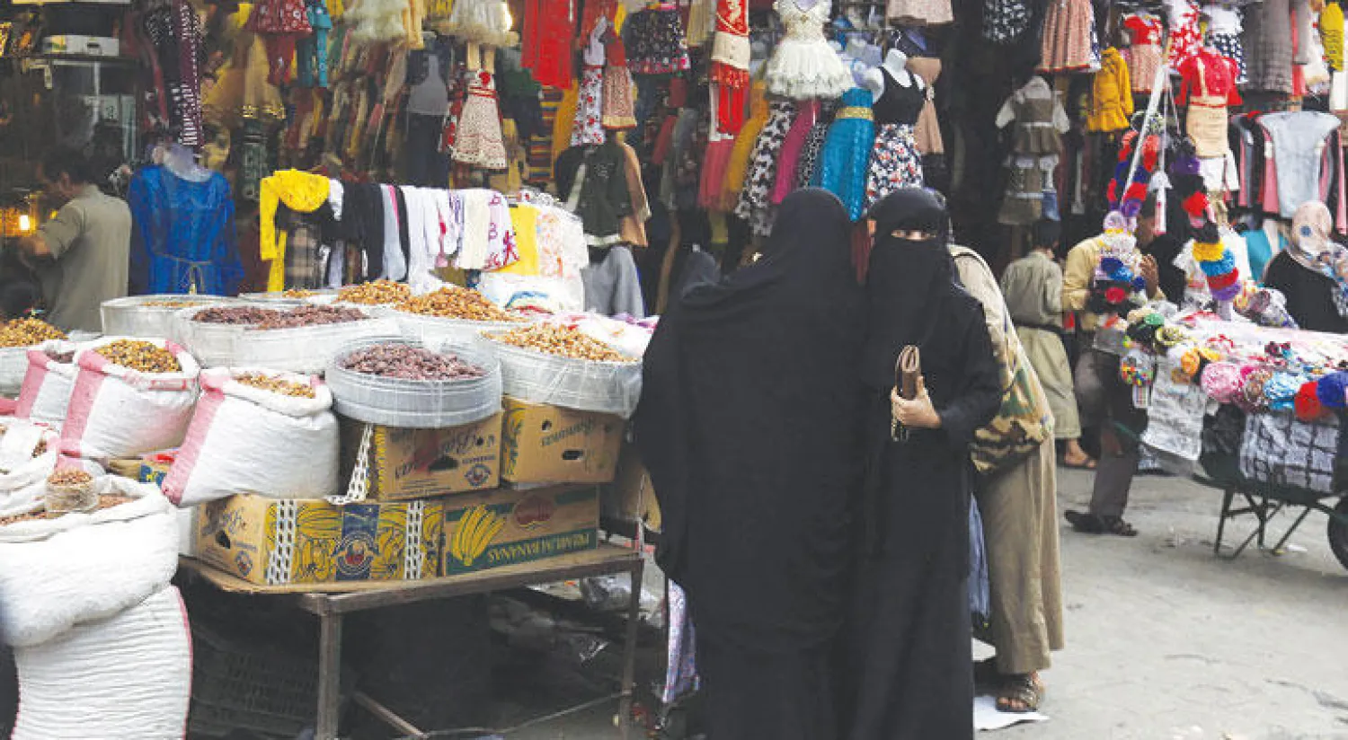 يمنيات يتسوقن في المدينة القديمة بالعاصمة صنعاء مساء أول من أمس قبل أيام من عيد الأضحى المبارك (إ.ب.أ)