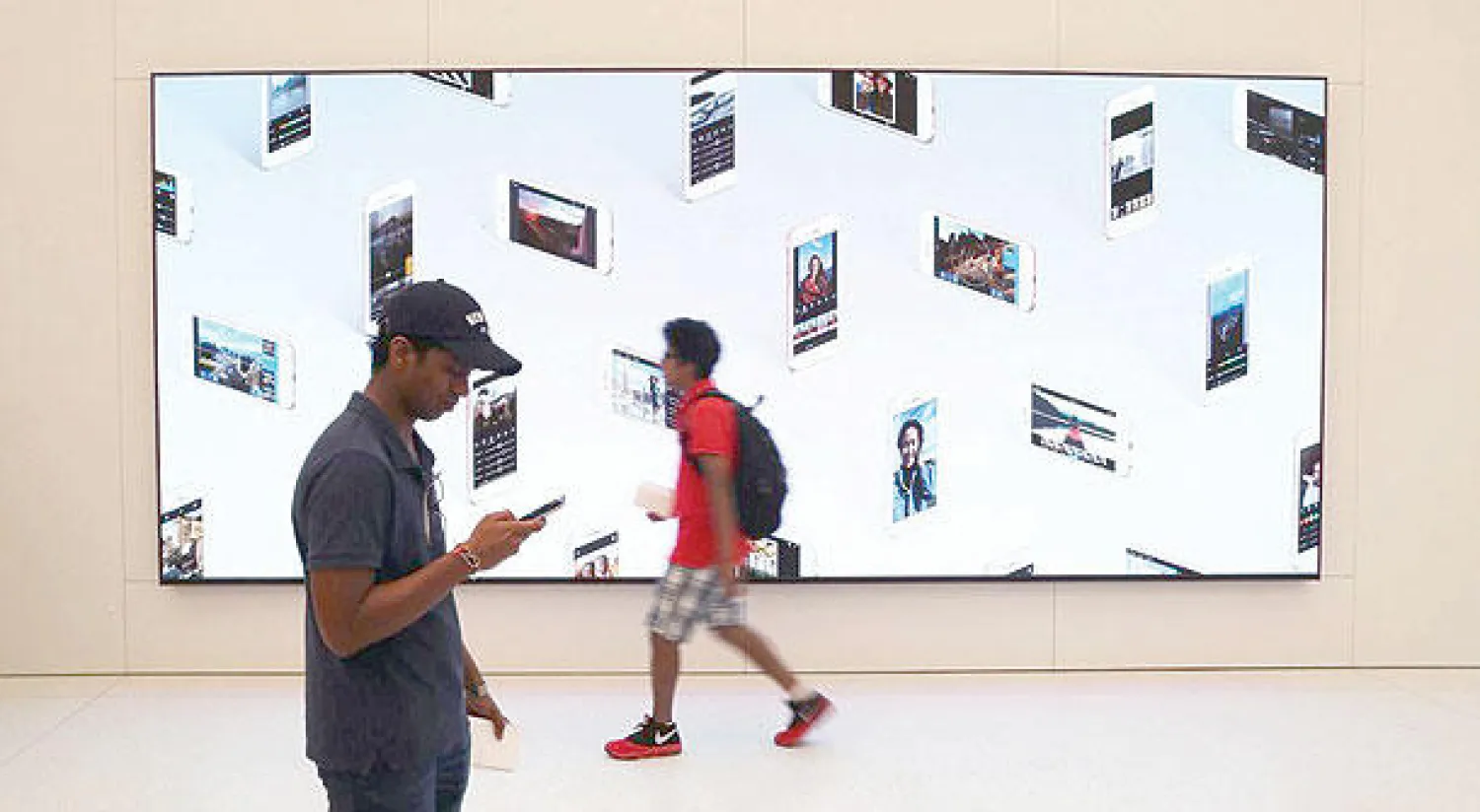 شخصان يمران أمام لوحة إعلانية بالولايات المتحدة الأميركية (رويترز)