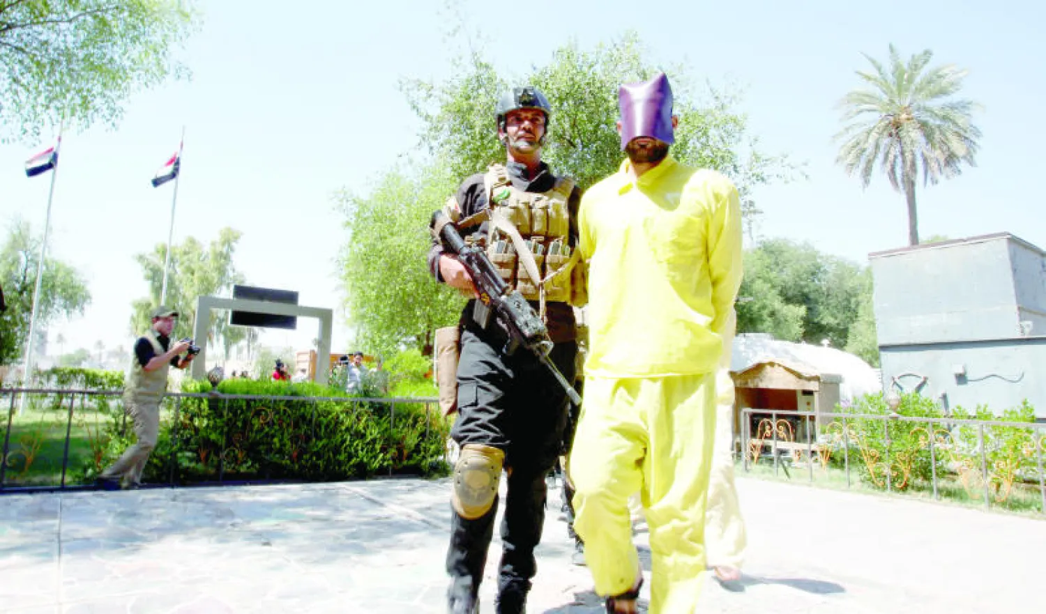 عنصر أمن عراقي يقتاد أحد المشتبه بانتمائهم لـ«داعش» في مقر الاستخبارات العسكرية ببغداد (رويترز)