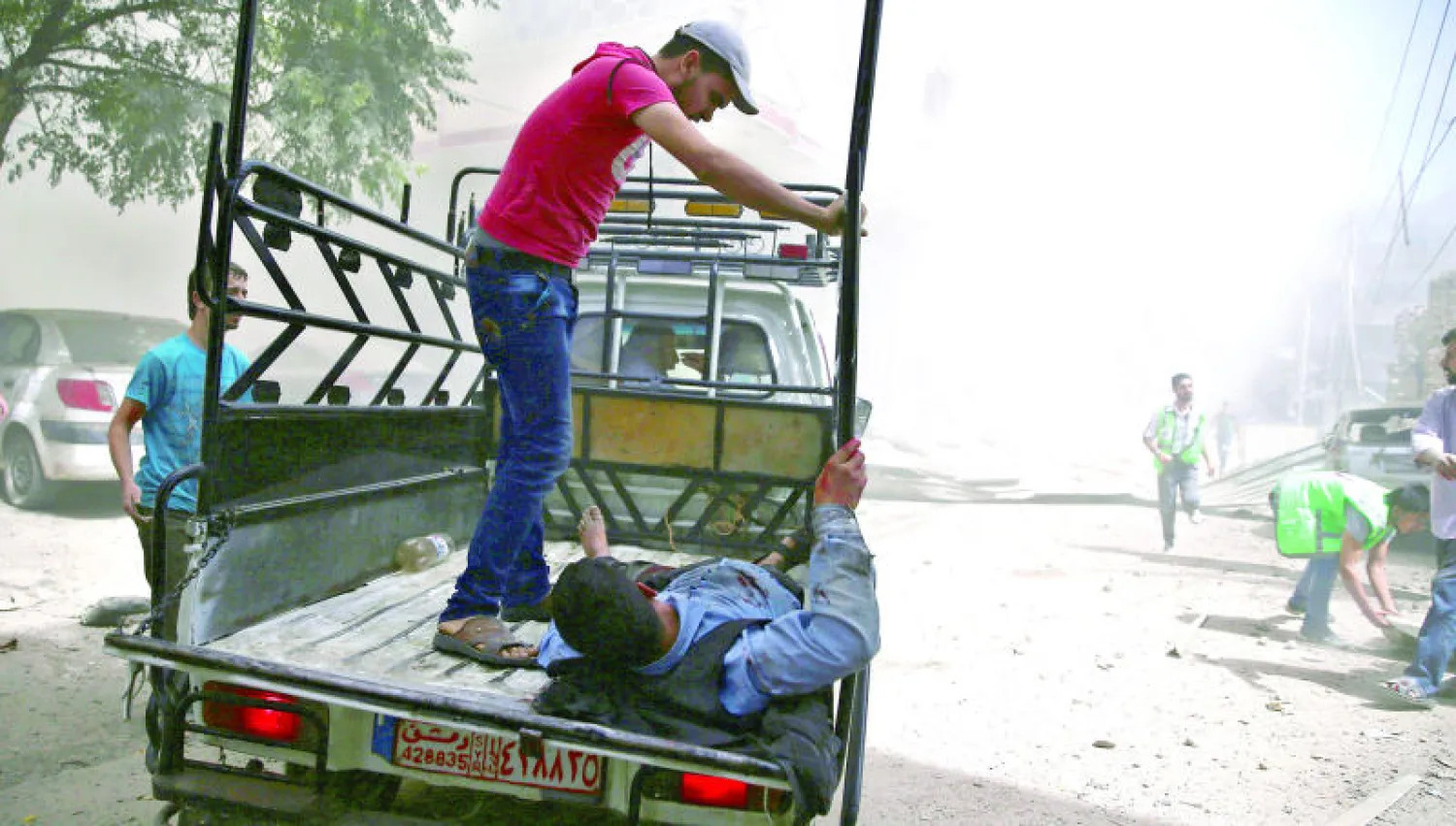 سوري ينقل صديقه المصاب على متن عربة نصف نقل في دمشق أمس (رويترز)
