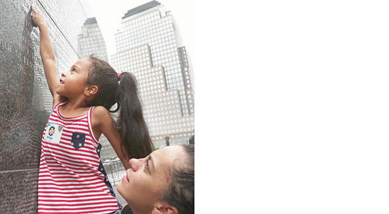 طفلة تشير الى اسم جدها على جدار يحمل أسماء ضحايا هجمات 11 سبتمبر في موقع مركز التجارة العالمي بنيويورك أول من أمس (أ.ف.ب)