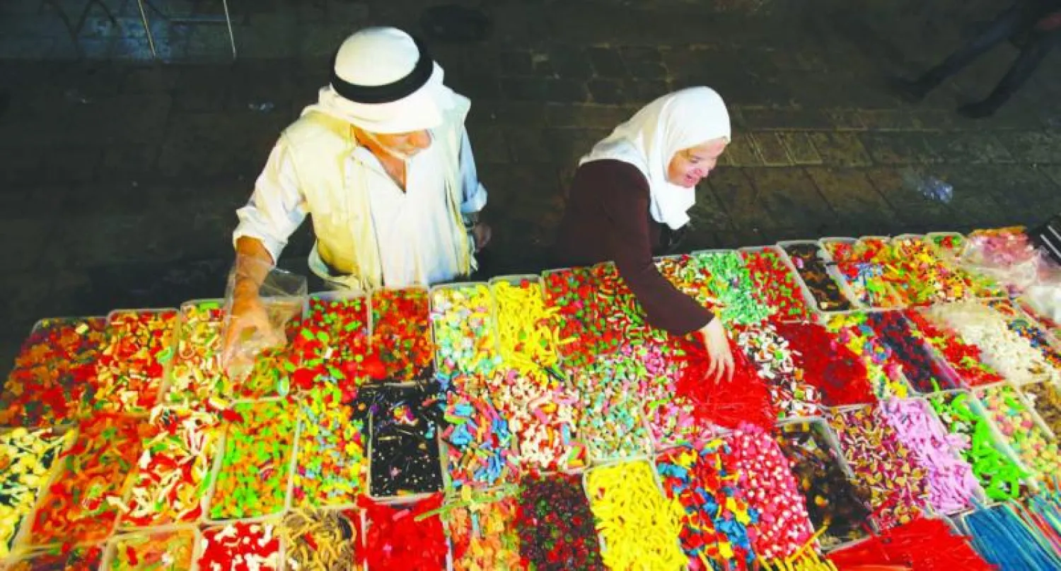 فلسطينيان يشتريان الحلويات استعدادا لعيد الأضحى بمدينة القدس المحتلة بأكملها من إسرائيل منذ عام 1997 (أ.ف.ب)