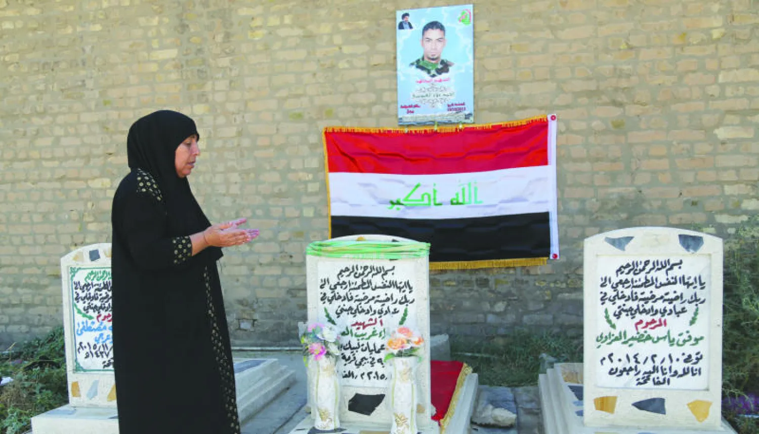 عراقية تزور قبر قريب لها بمقبرة ببغداد في أول أيام عيد الأضحى المبارك أمس (أ.ب)