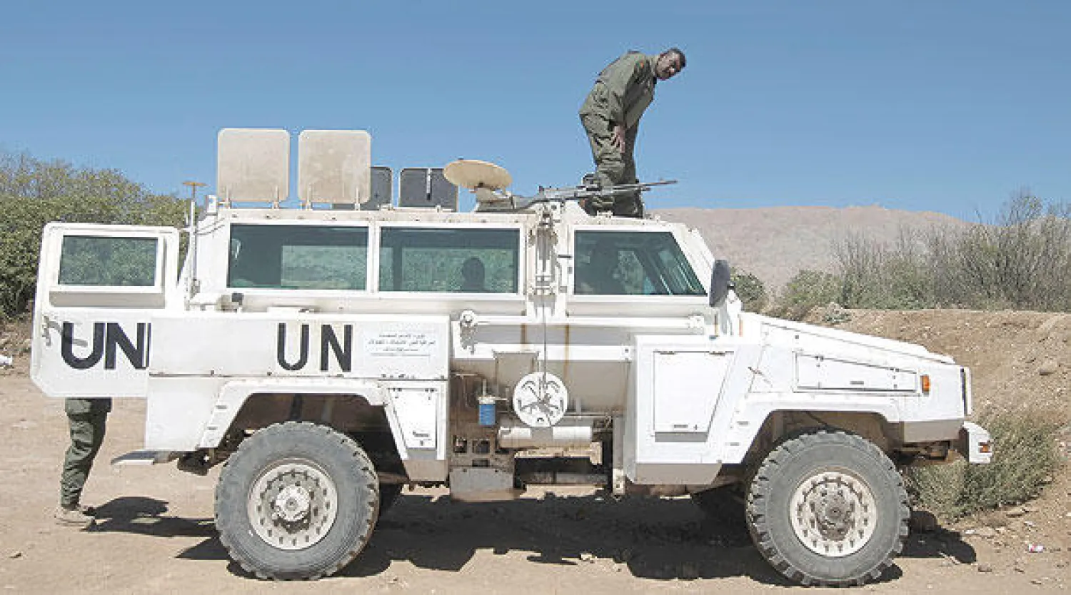 عنصر من قوات حفظ السلام التابعة للأمم المتحدة يقف على سيارته ويراقب الحدود مع سوريا  بالقرب من قرية مجدل شمس في القطاع الذي تحتله إسرائيل من هضبة الجولان (أ.ف.ب)