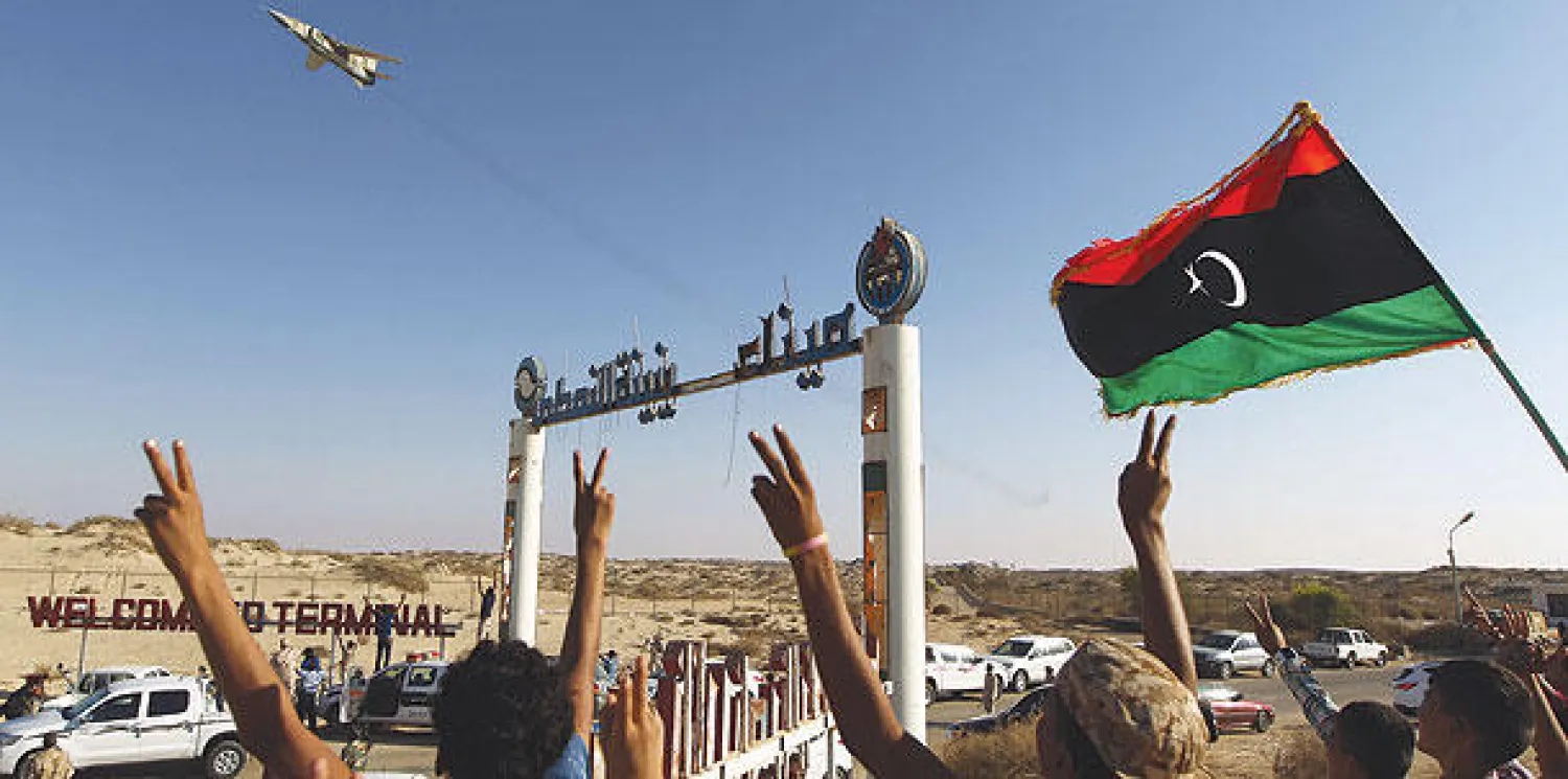 مواطنون ليبيبون يرفعون العلم الليبي احتفالا بتحليق مقاتلة فوق حقل الزويتينة النفطي (أ.ف.ب)