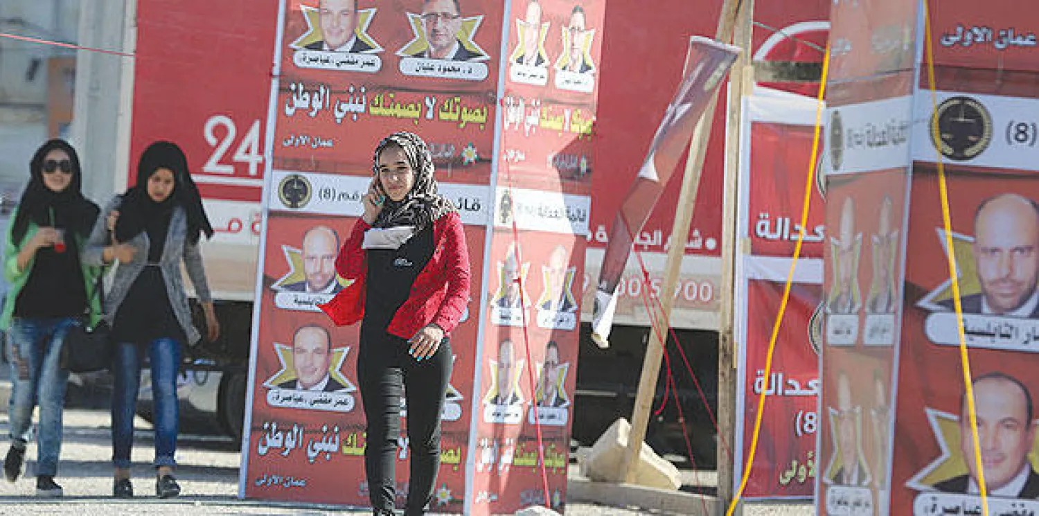 مواطنة أردنية تمر بالقرب من ملصقات انتخابية في عمان أمس (أ.ف.ب)