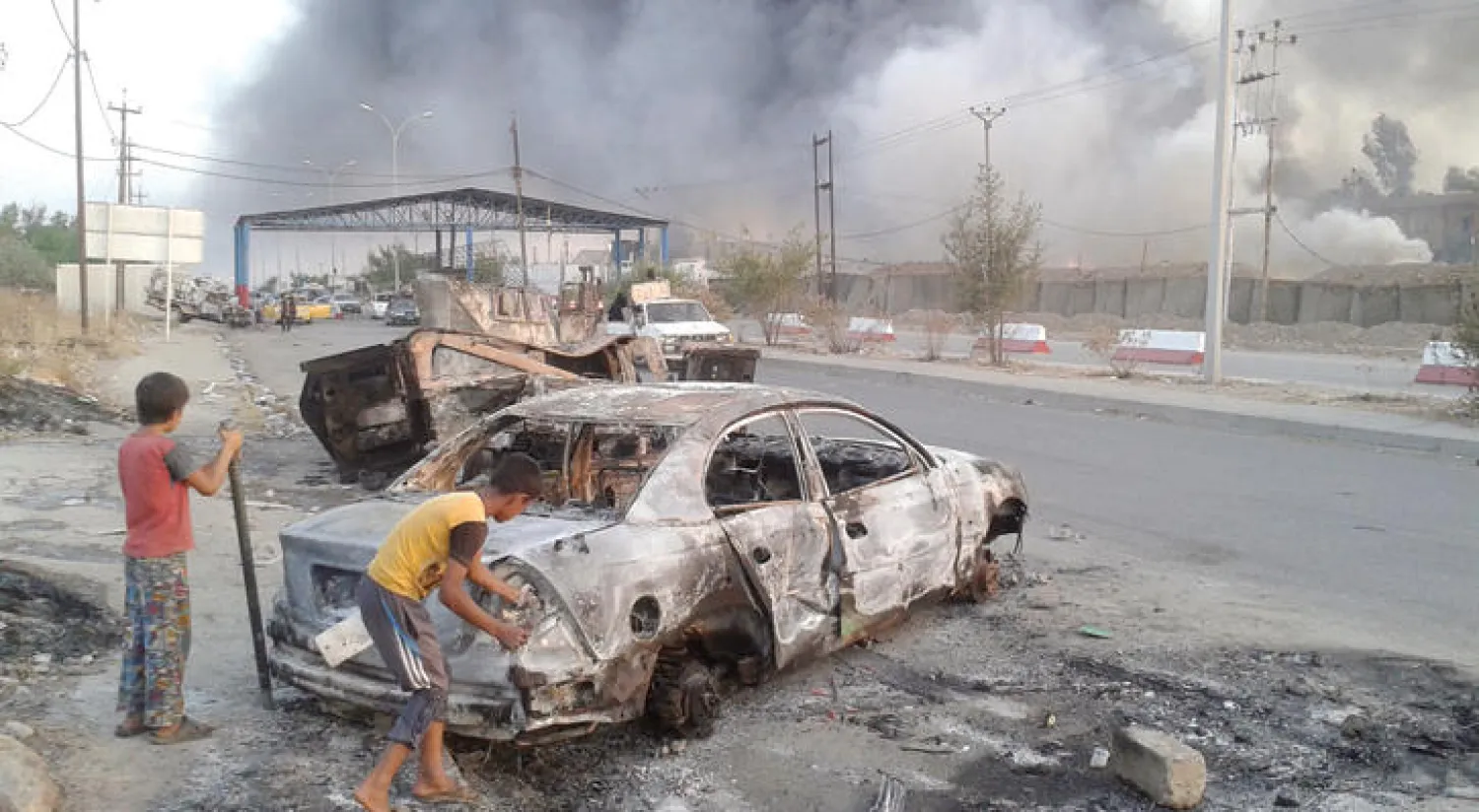 فتيان يلعبان قرب حطام سيارة وسط الموصل (رويترز)