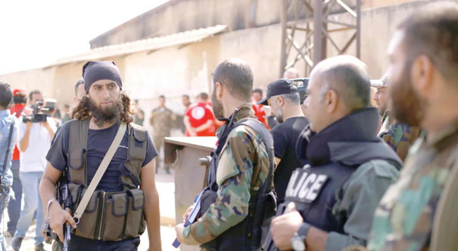 مقاتل من المعارضة السورية يمر أمام جنود من جيش النظام السوري أمس قبل إخلاء منطقة وسط حمص، بعد التوصل لاتفاق بين الطرفين  (رويترز)