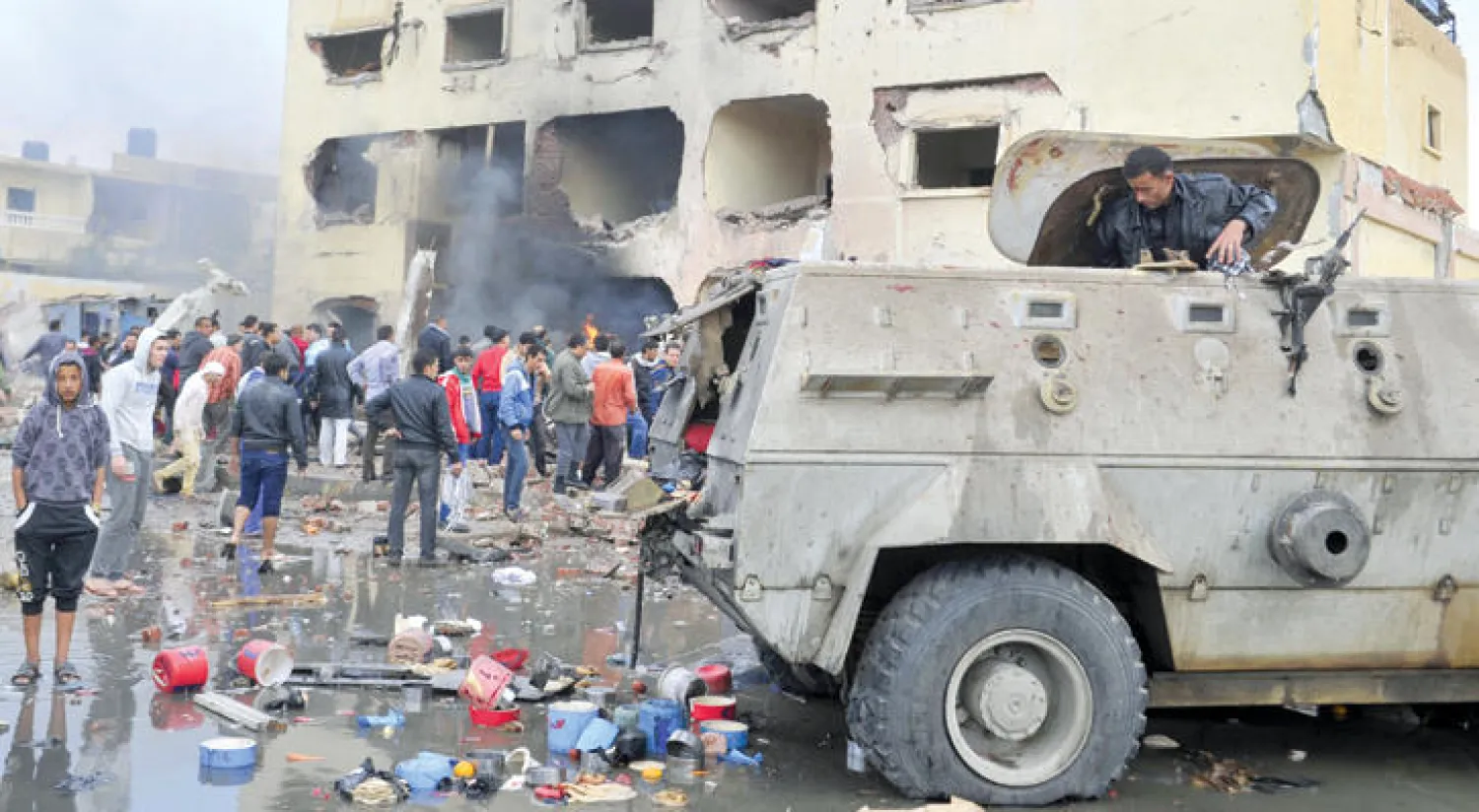 مصريون يعاينون الدمار الذي لحق بمركز الشرطة في شمال سيناء ومدرعة تابعة للمركز إثر عملية تفجير إرهابية في أبريل الماضي (أ.ف.ب)