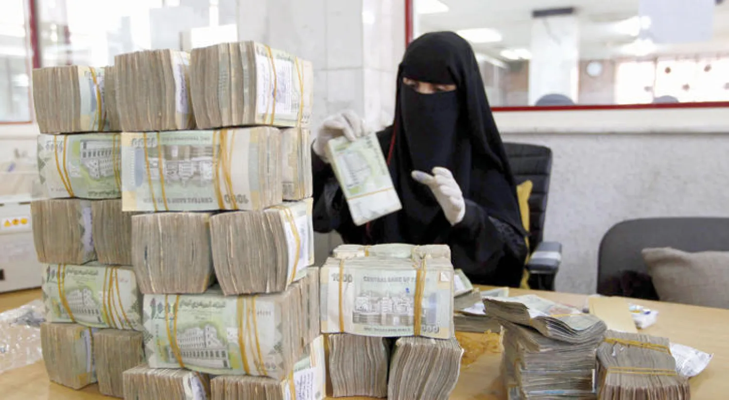 موظفة تعد النقود داخل البنك المركزي في صنعاء (أ ف ب)