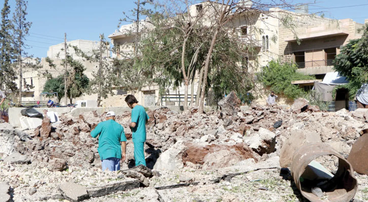 سوريان يعاينان حجم الدمار الذي لحق بأكبر مستشفيات شرق حلب جراء البراميل المتفجرة التي اسقطها طيران النظام أمس (غيتي)