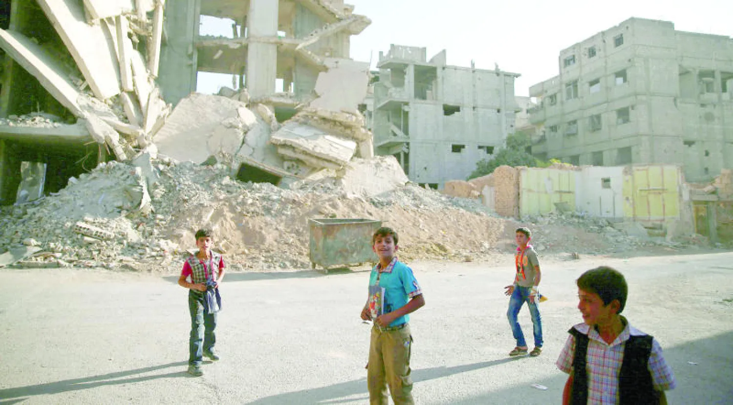 أطفال من بلدة زملكا بريف دمشق يلهون بالقرب من أنقاض الأبنية التي ضربتها غارات طيران النظام أول من أمس (رويترز)