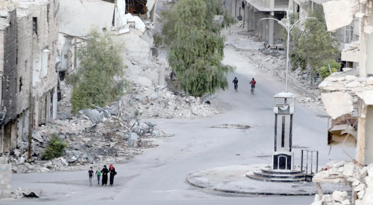 سكان من (طريق الباب) في حلب يعبرون الحي المدمر بفعل استهدافه بغارات الطيران  (رويترز)