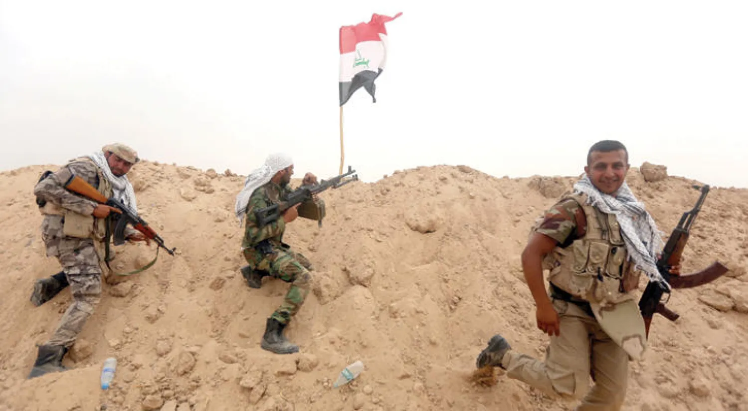 عناصر تابعة لقوات الحشد الشعبي يتخذون مواقع لهم أثناء معارك في جبهة الثرثار على حدود محافظة الأنبار ({غيتي})