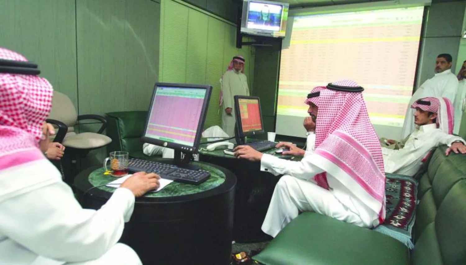 مستثمرون سعوديون يتابعون حركة الأسهم والسندات على شاشة للتداول («الشرق الأوسط»)