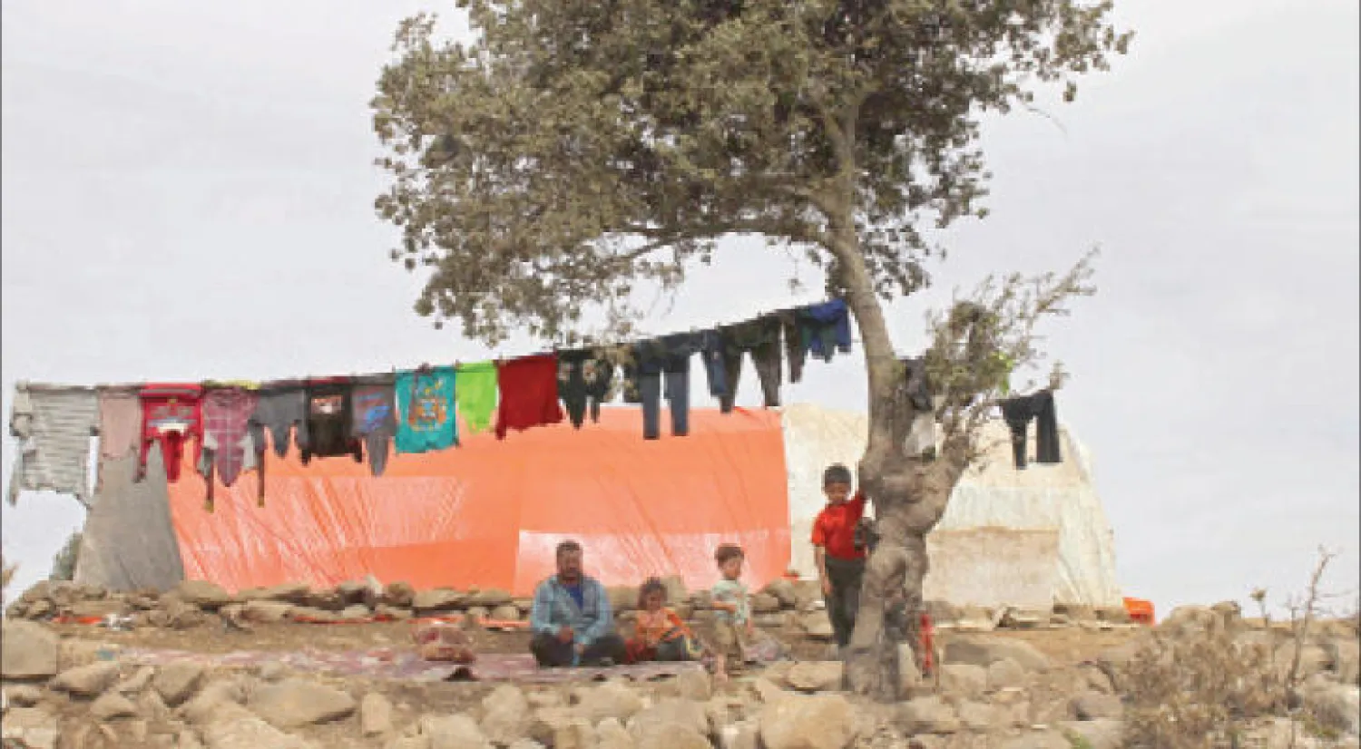 نازح سوري يجلس مع أبنائه خارج خيمته في مخيم أقيم بريف القنيطرة هربا من المعارك في غوطة دمشق الشرقية أول من أمس (أ.ف.ب)