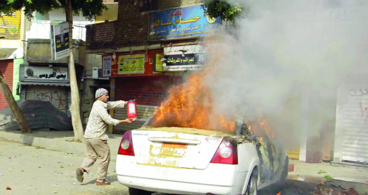 مصري يحاول إطفاء النيران المشتعلة في سيارة إثر اشتباكات شهدتها منطقة المطرية شمال القاهرة بين مؤيدين لجماعة الأخوان المسلمين وقوات الأمن المصرية  العام الماضي (غيتي)