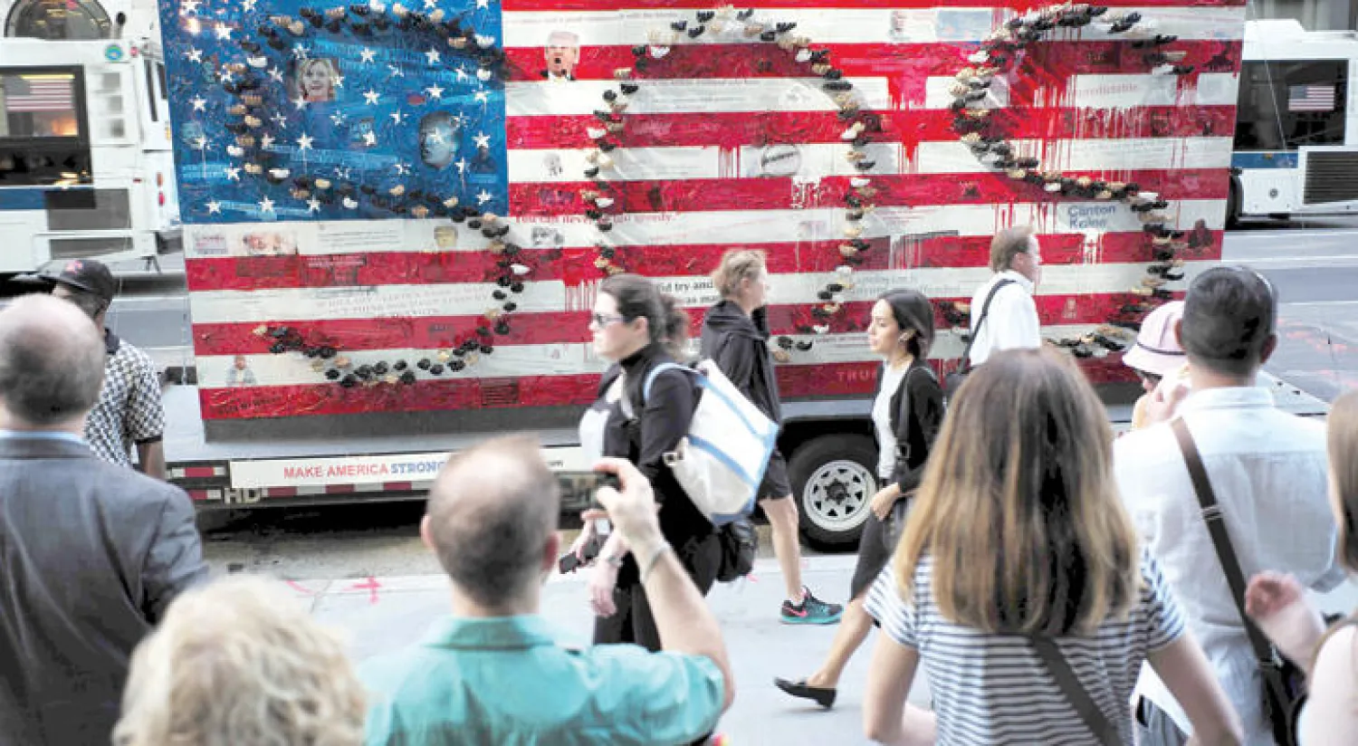 أميركيون يمرون بجانب لوحة فنية لديفيد داتونا حول الانتخابات الأميركية قرب برج ترامب في نيويورك (أ.ف.ب)