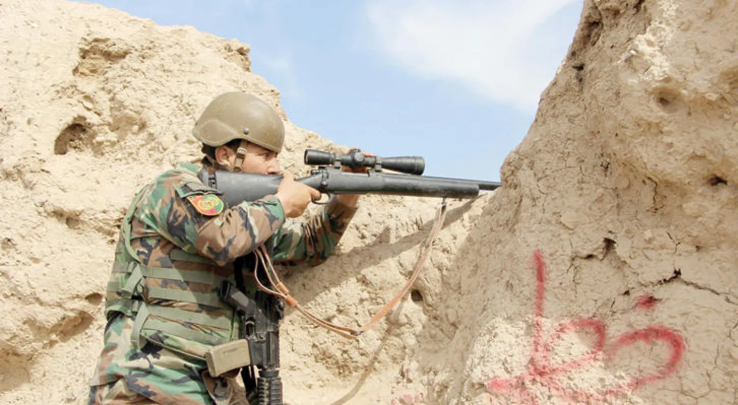 جندي أفغاني يصوب بندقيته إلى مواقع عناصر «طالبان» في ولاية هلمند أمس (إ.ب.أ)