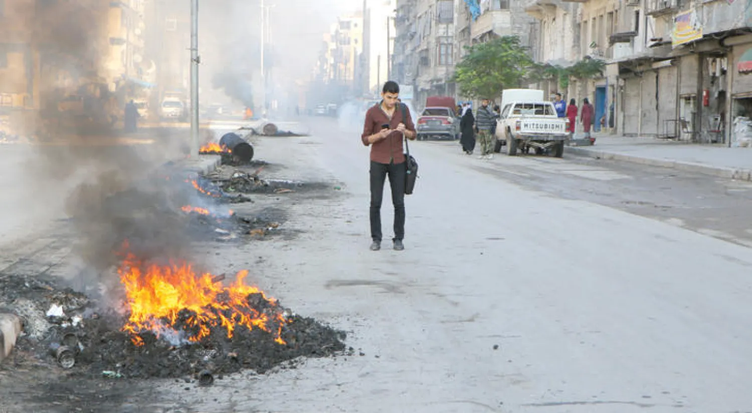 عناصر من المعارضة تحاول تضليل القاذفات الروسية ومنعها من استهدافهم بإشعال النار في إطارات سيارات بحلب (غيتي)