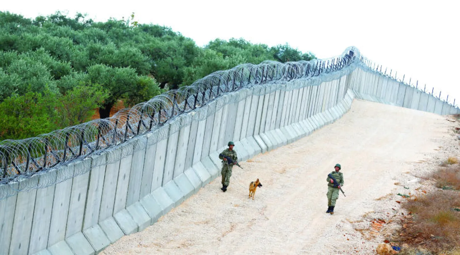 دورية من الوحدة ( كي9) التركية تحرس الجدار على خط الحدود مع سوريا بالقرب من قرية بيسارسلان جنوب شرقي تركيا (رويترز)