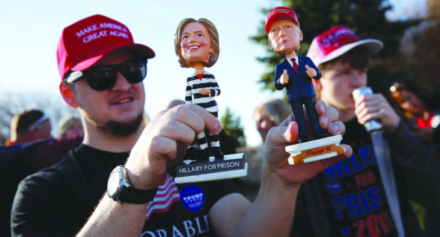 أحد أنصار ترامب يحمل مجسمًا لكلينتون بلباس السجن في تجمع انتخابي بمينابوليس أمس (رويترز)