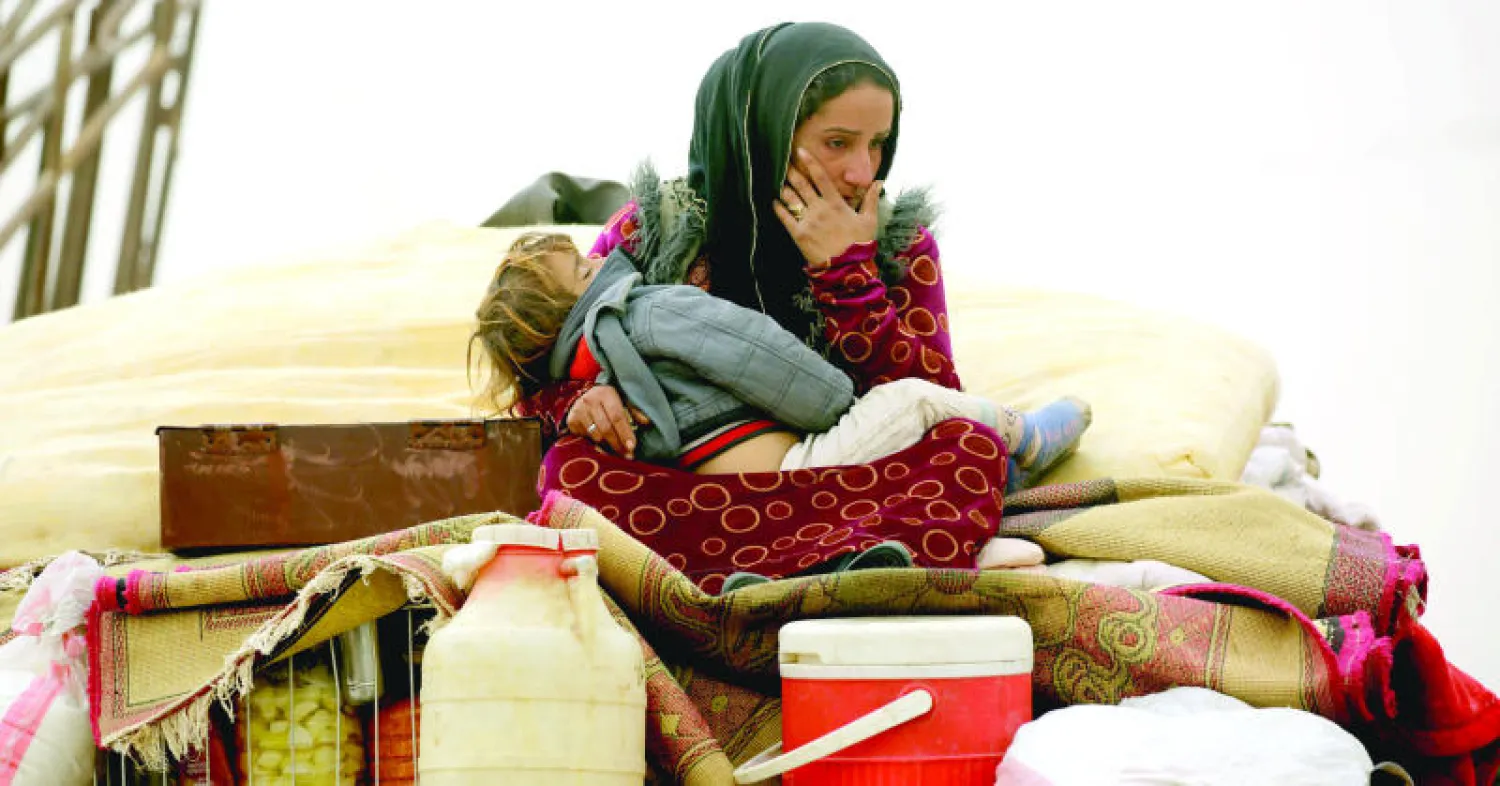سورية هاربة من الرقة تحتضن طفلها وتجلس فوق أمتعتها في أحد معسكرات النزوح في الشمال السوري (أ. ف. ب)