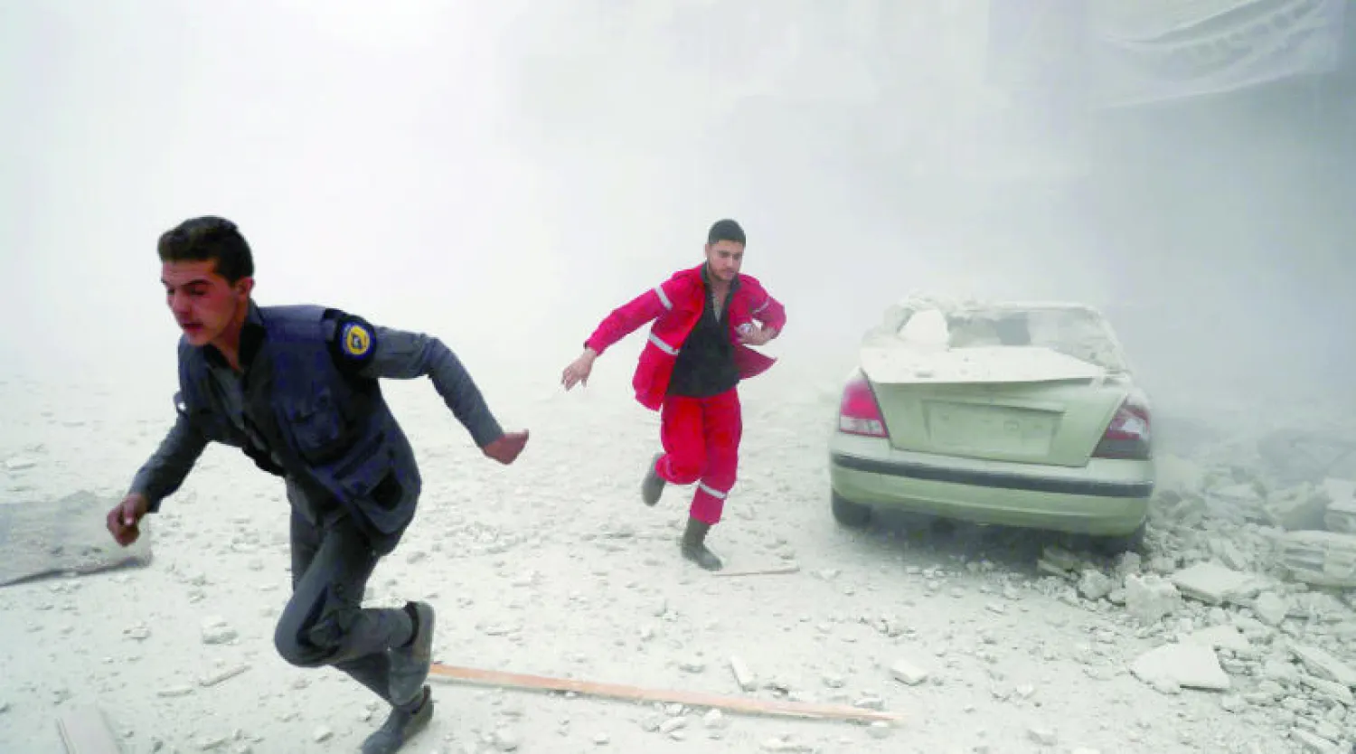 عنصران من الدفاع المدني والصليب الأحمر يبحثان عن ضحايا خلفهم قصف الطيران الروسي والسوري على دوما أمس (أ. ف. ب)