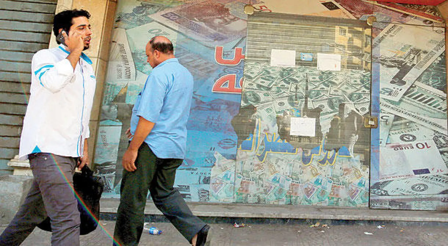 مصريان يمران امام محل صرافة في أحد أحياء القاهرة (رويترز)