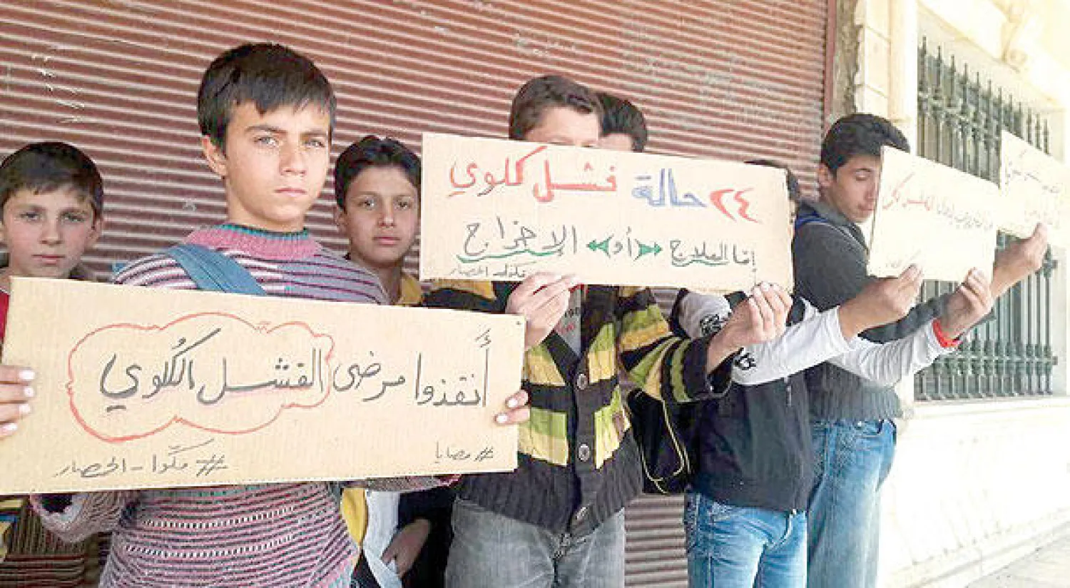 أطفال بلدة مضايا المحاصرة بريف دمشق يرفعون لافتات تطالب بفك الحصار عن البلدة التي أنهكها الجوع والمرض (مواقع تواصل اجتماعي)