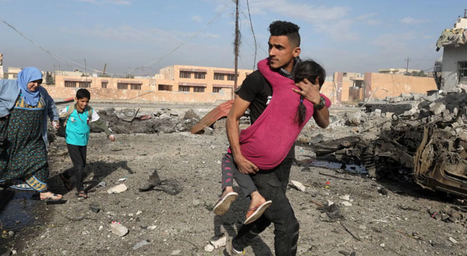 جندي عراقي يحمل صبية اصيبت بجروح في هجوم نفذه انتحاري خلال الاشتباكات في حي التحرير في الموصل أمس (رويترز)