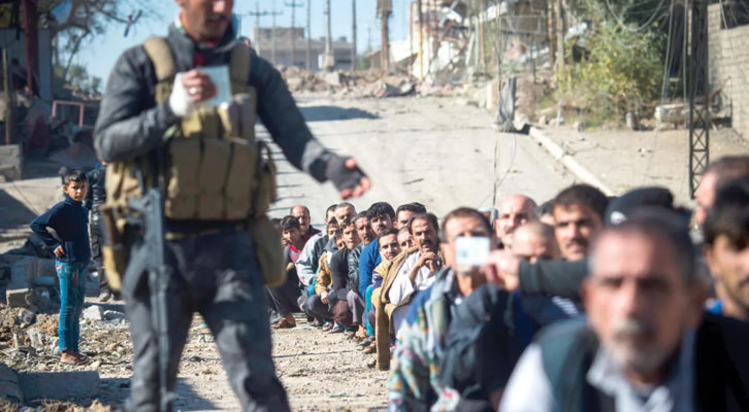 جندي عراقي يجمع هويات رجال احتجزتهم القوات الأمنية في حي كركوكلي بالجانب الأيسر من الموصل أمس (أ.ف.ب)