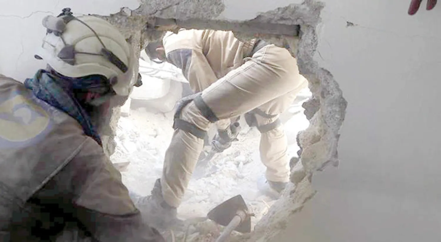 عناصر من الدفاع المدني ينقذون الضحايا من تحت ركام بناء تعرض لغارة جوية بالقنابل المظلية استهدفت حي الميسر وأحياء أخرى في حلب أمس (مركز حلب الإعلامي)