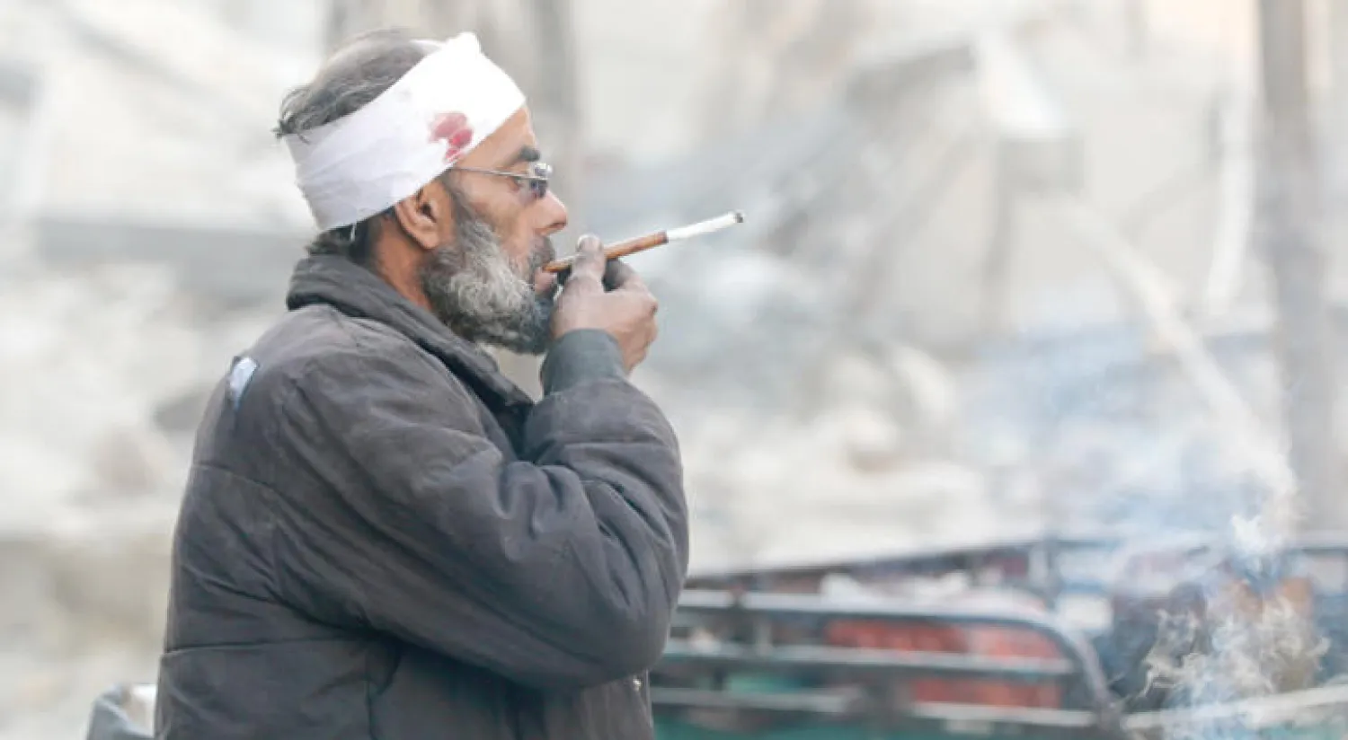 بائع متجول تبدو عليه آثار القصف على القسم المحاصر من حلب قرب عربته أمس (رويترز)