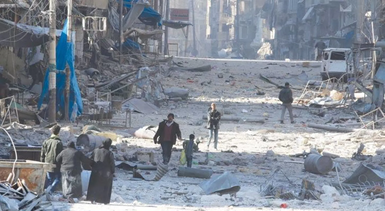 سوريون يشقون طريقهم وسط الأنقاض حاملين أمتعتهم هربا من المعارك في شرق حلب أمس (رويترز)