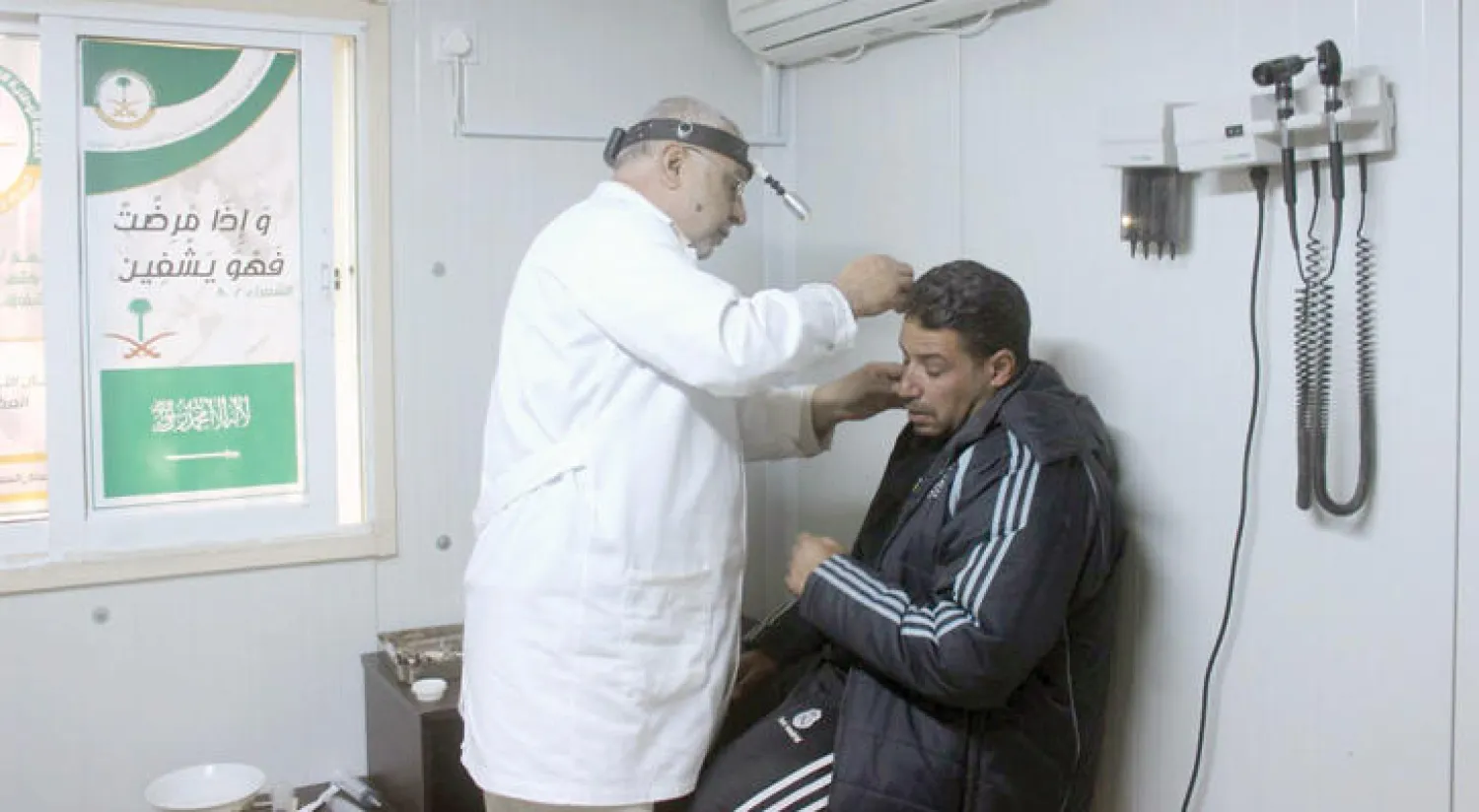 أحد الأطباء في العيادات التخصصية السعودية خلال إجرائه الفحوصات الطبية للاجئ سوري في مخيم الزعتري (واس)