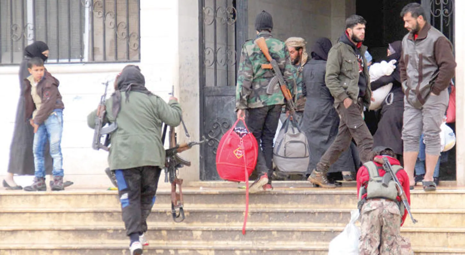 مقاتلون مع عائلاتهم يصلون إلى إدلب بعد إجلائهم من خان الشيخ (أ.ف.ب)