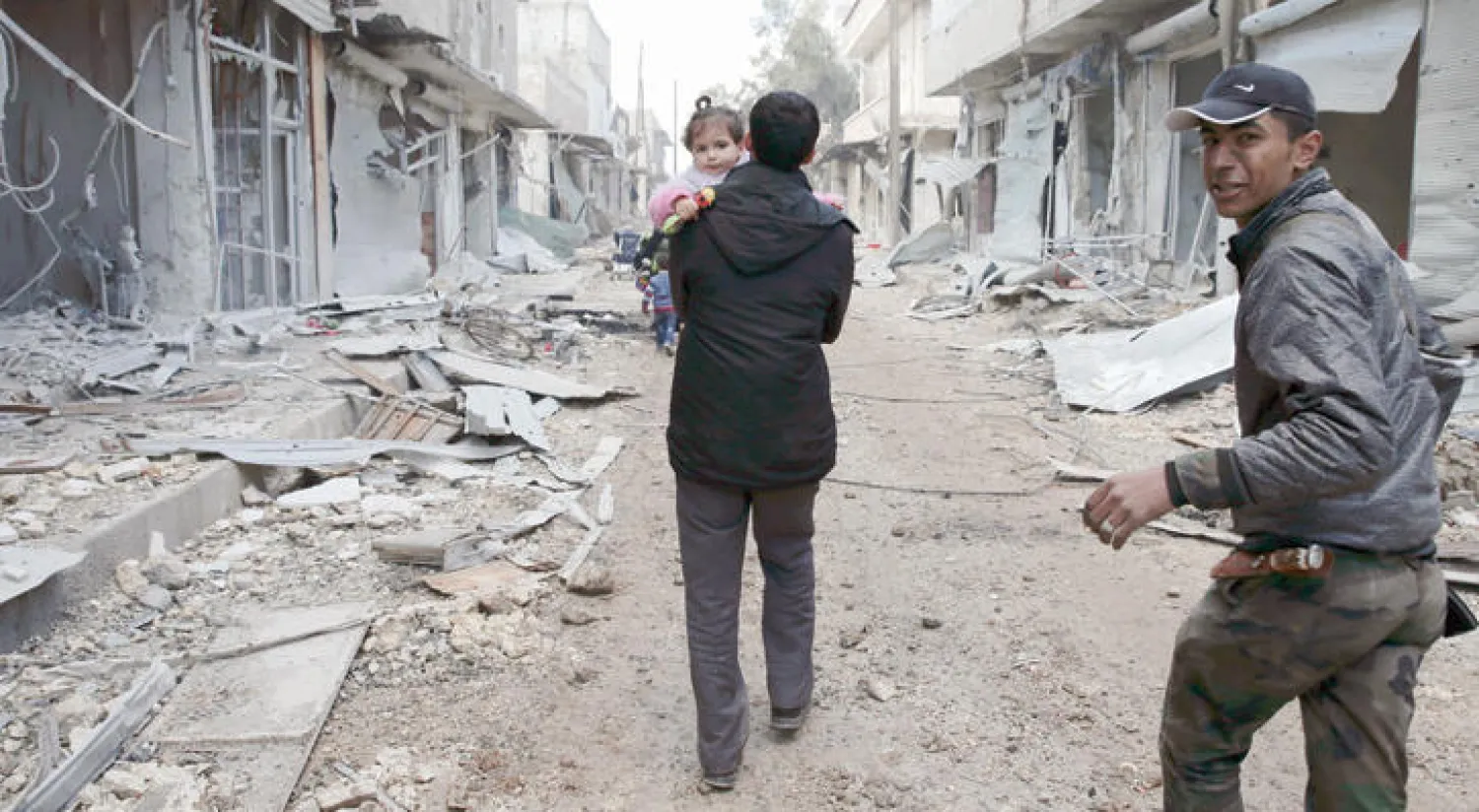 سوري يحمل ابنته هاربا من شرق حلب (أ.ب)