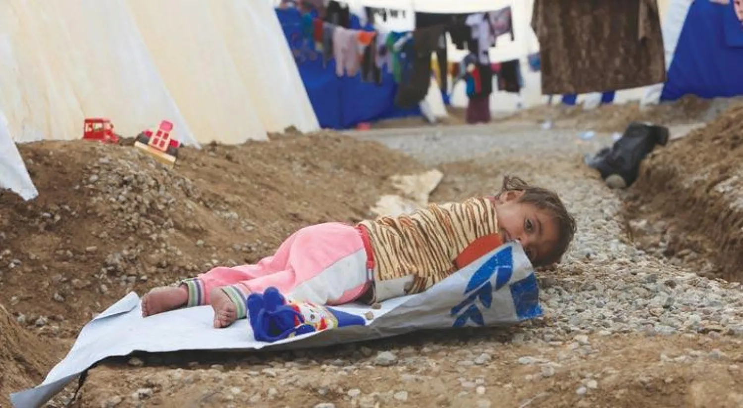 طفل عراقي هربت عائلته من مناطق يسيطر عليها «داعش» في الموصل يستلقي وسط خيام معسكر الخازر (رويترز)