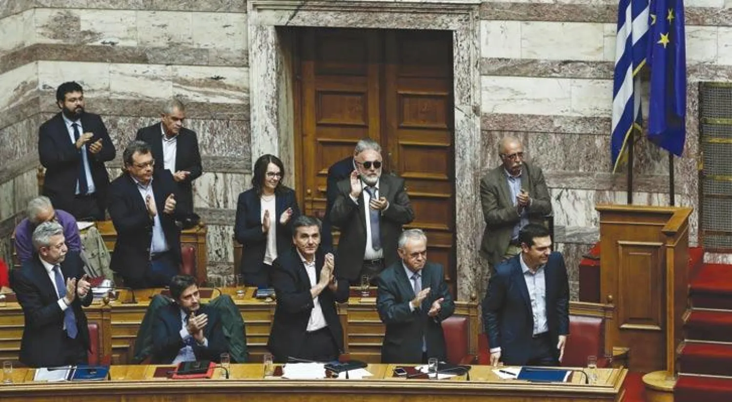 أعضاء البرلمان اليوناني يصفقون لرئيس الحكومة ألكسيس تسيبراس بعد خطابه في البرلمان إثر إقرار موازنة 2017 مساء أول من أمس (إ.ب.أ)