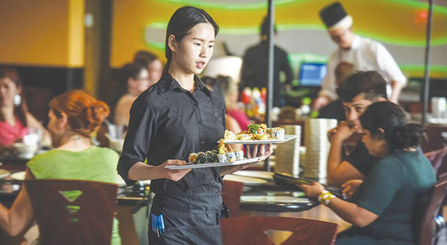 نادلة في أحد المطاعم الصينية تقدم السوشي لبعض الزبائن ({غيتي})