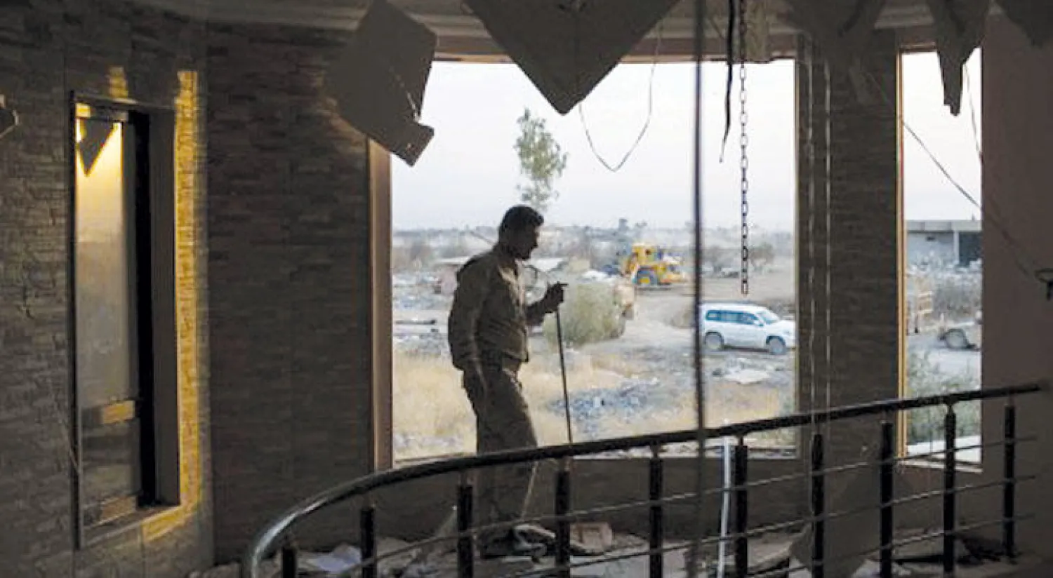 عنصر من البيشمركة يعاين الدمار الذي خلفته «داعش» في منزل ببعشيقة (أ.ب)