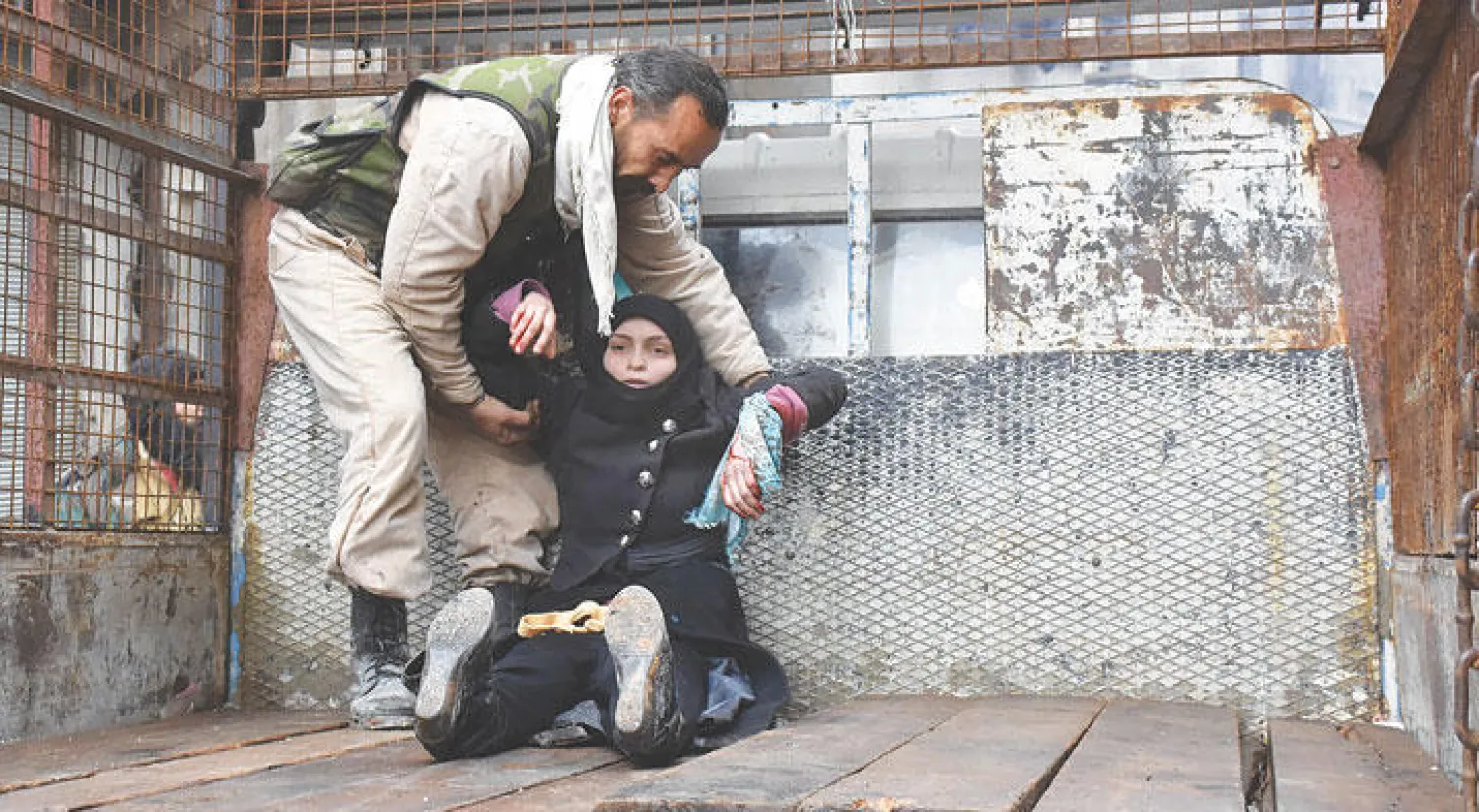 رجل يسعف امرأة أصيبت أثناء محاولتها الفرار من المواجهات الدائرة بين قوات النظام وفصائل المعارضة في إحدى المناطق التي لا تزال تحت سيطرة المعارضة بحلب الشرقية أمس (أ.ف.ب)