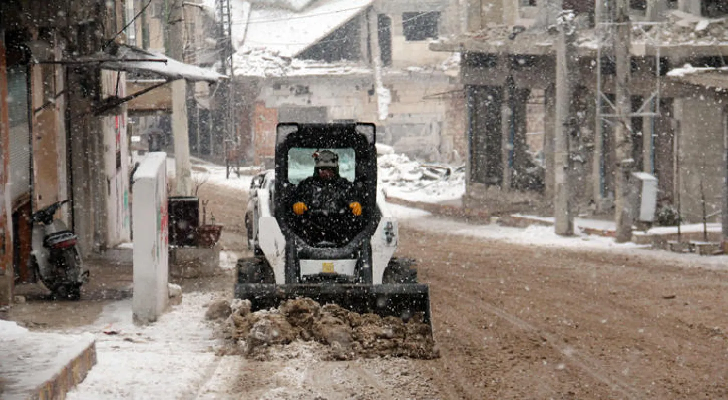 سوري من ريف إدلب ينظف الطريق بعربته من الثلج الذي تراكم بفعل عاصفة ضربت البلاد اخيراً (إ ف ب)
