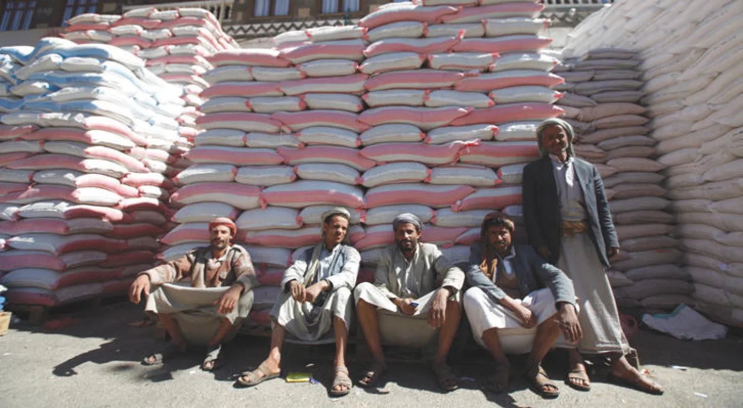 عمال يجلسون أمام أكياس الطحين في سوق الجملية بصنعاء (رويترز)