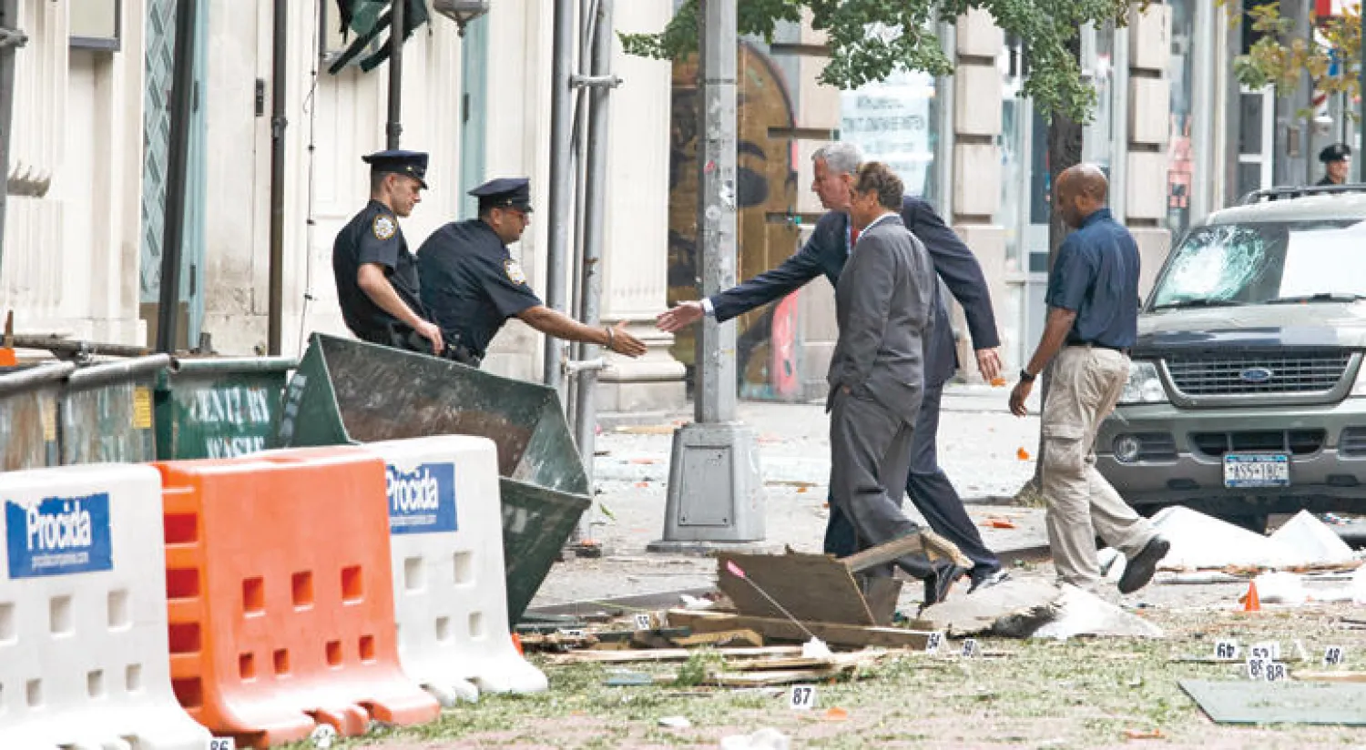 بيل دي بلاسيو عمدة مدينة نيويورك والحاكم آندرو غومو في سبتمبر الماضي مع أعضاء الشرطة في موقع انفجار منطقة تشيلسي وقيل حينها إن التفجير ليس مرتبطًا بالإرهاب (نيويورك تايمز)
