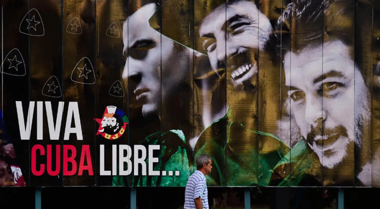 كوبي يمر من أمام ملصق يحمل صورة تشي غيفارا بساحة الثورة في مدينة هافانا (أ.ف.ب)
