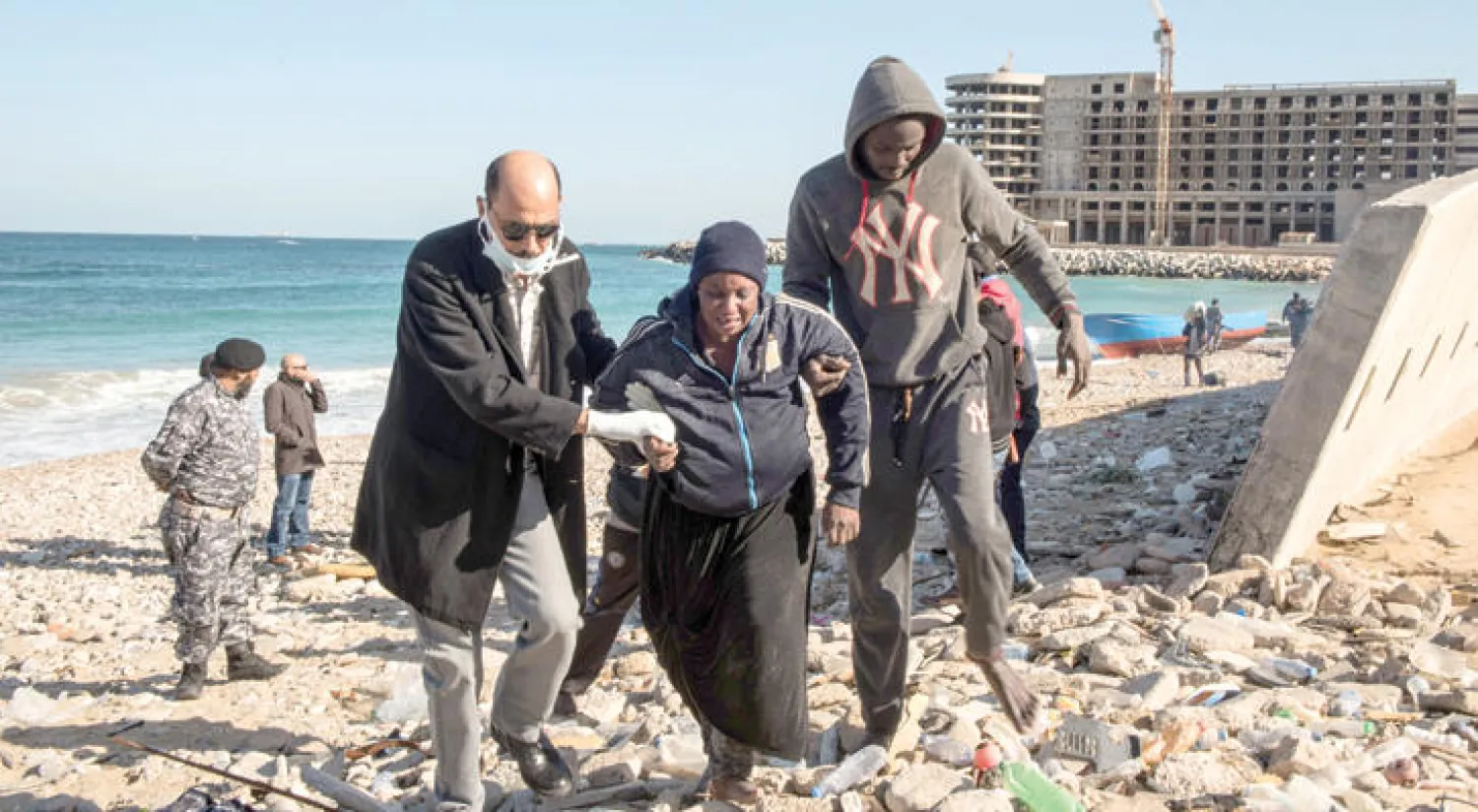 ليبي يساعد مهاجرة غير شرعية بعد أن انقلب القارب الذي كان يقلها بالقرب من الشواطئ الليبية (رويترز)