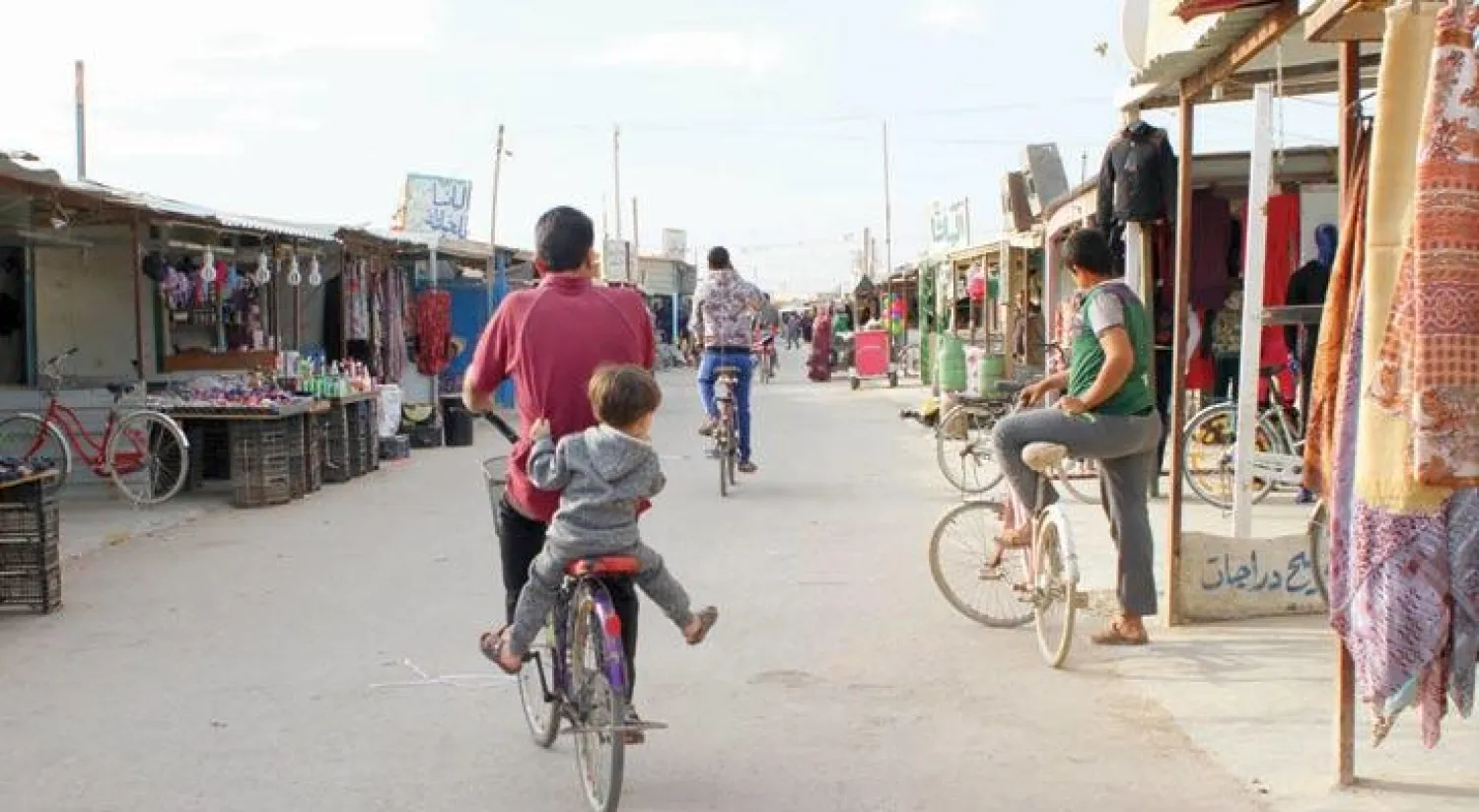 لاجئون سوريون يسيرون بالقرب من أحد أسواق مخيم الزعتري بالأردن الذي يؤوي حوالي 80 الف لاجئى (رويترز)