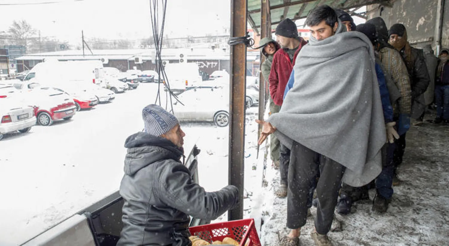 لاجئون يقفون في طابور للخبز خارج مستودع مهجور في بلغراد بصربيا، أمس، حيث ينتظرون فتح الحدود لاستكمال رحلتهم إلى دول أوروبية أخرى (غيتي)